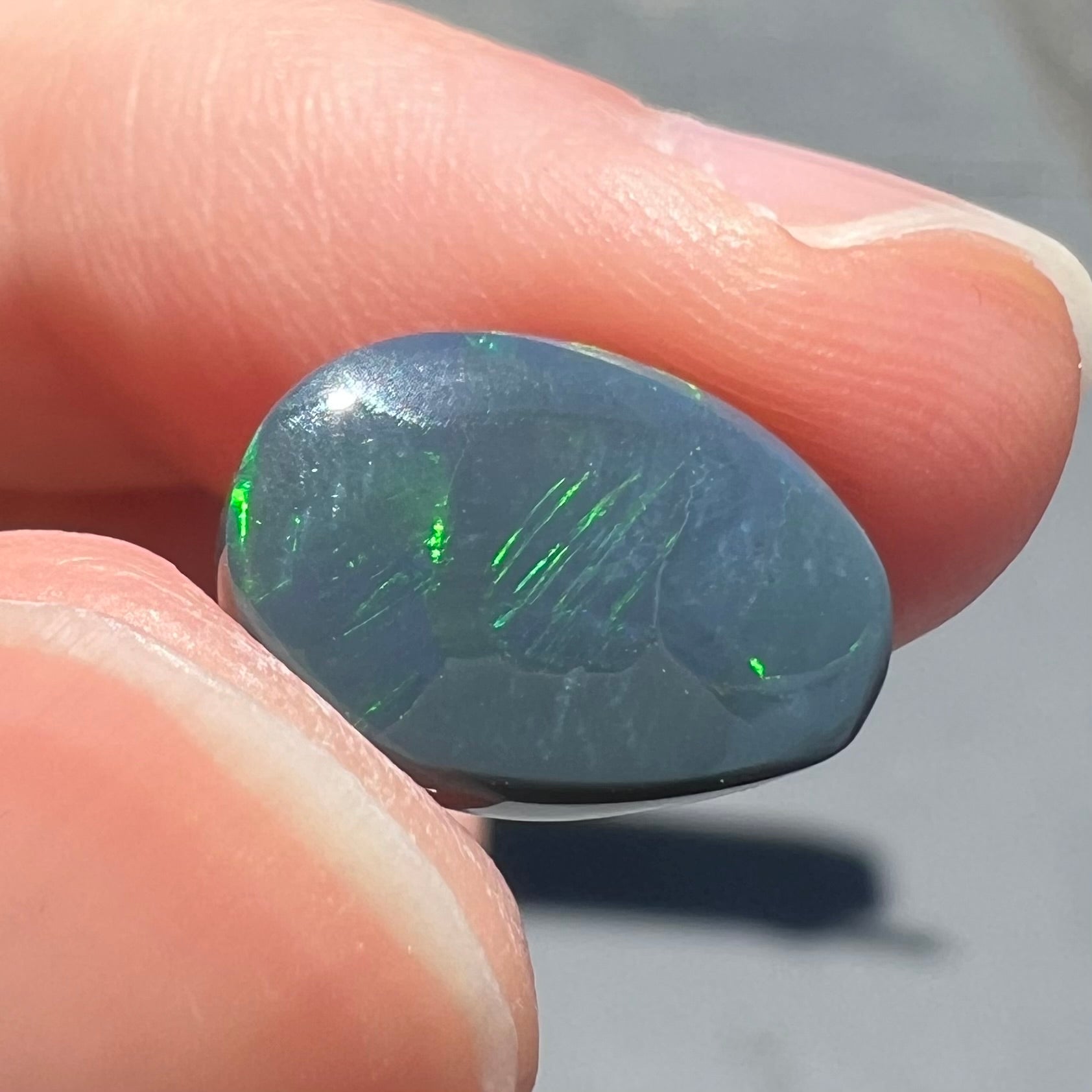 A loose, freeform cut black opal stone from Lightning Ridge, Australia.