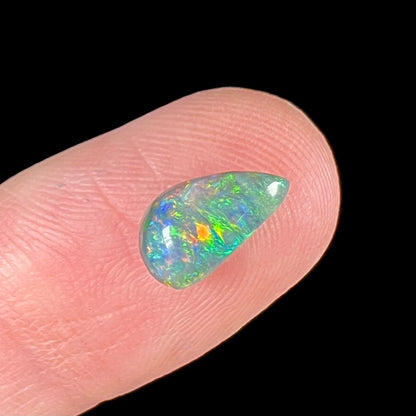 A black opal gemstone from Lightning Ridge, Australia.  The opal is a freeform cut.