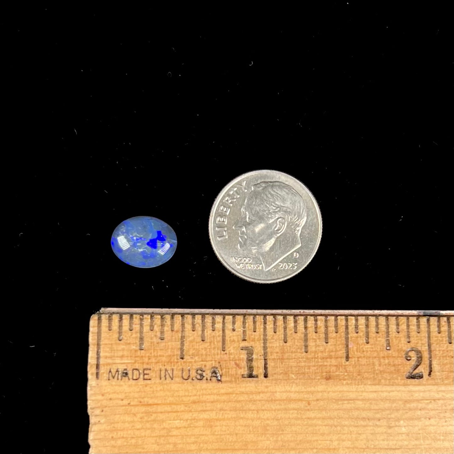 A loose, oval cabochon cut black crystal opal from Lightning Ridge, Australia.