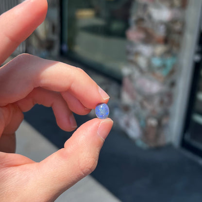 A loose, oval cabochon cut black crystal opal from Lightning Ridge, Australia.