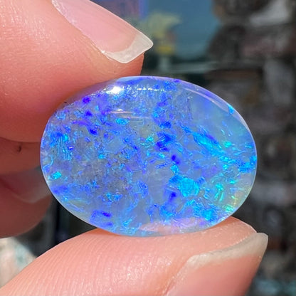 A loose, oval cabochon cut crystal opal from Lightning Ridge, Austalia that weighs 5.16 carats.  The stone has blue and purple colors.