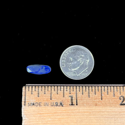 A loose, oval cabochon cut black opal stone that weighs 1.52 carats.  The opal plays blue colors.