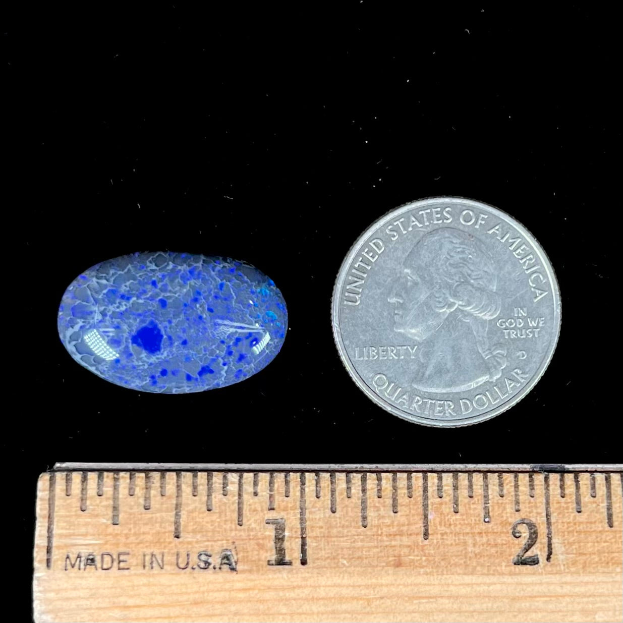 A loose, oval cabochon cut black opal from Lightning Ridge, Australia that weighs 13.09 carats.  The opal is blue.