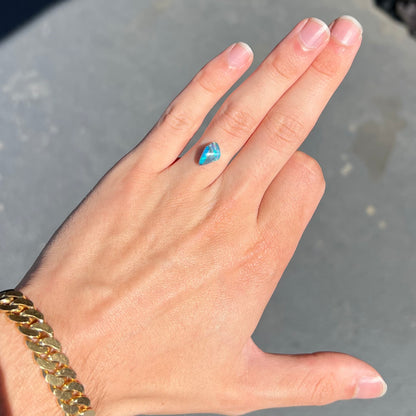 A 1.63 carat loose black opal stone from Lightning Ridge, Australia.  The opal is a freeform shape.