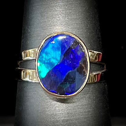 A ladies' split shank natural, Lightning Ridge, Australian black opal solitaire ring in yellow gold.