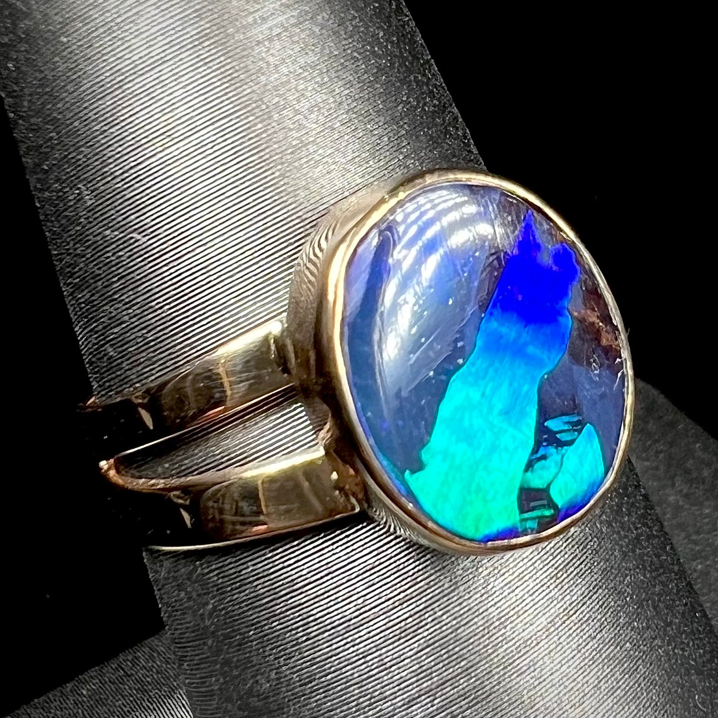 A ladies' split shank natural, Lightning Ridge, Australian black opal solitaire ring in yellow gold.