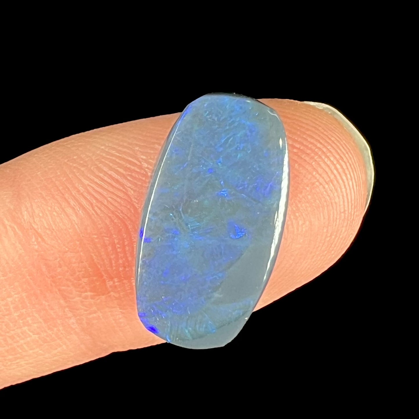 A loose, barrel shaped black opal stone from Lightning Ridge, Australia that weighs 5.25 carats.