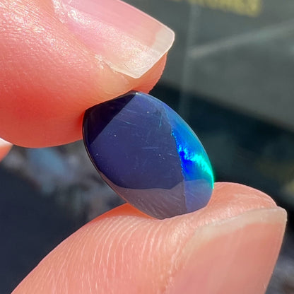 A loose, oval cabochon cut black opal from Lightning Ridge, Australia.  The opal has an N2 body tone.