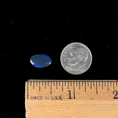 A loose, oval cabochon cut black opal from Lightning Ridge, Australia.  The opal has an N2 body tone.