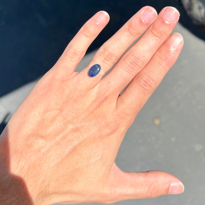 A loose, oval cabochon cut black opal from Lightning Ridge, Australia.  The opal has an N2 body tone.