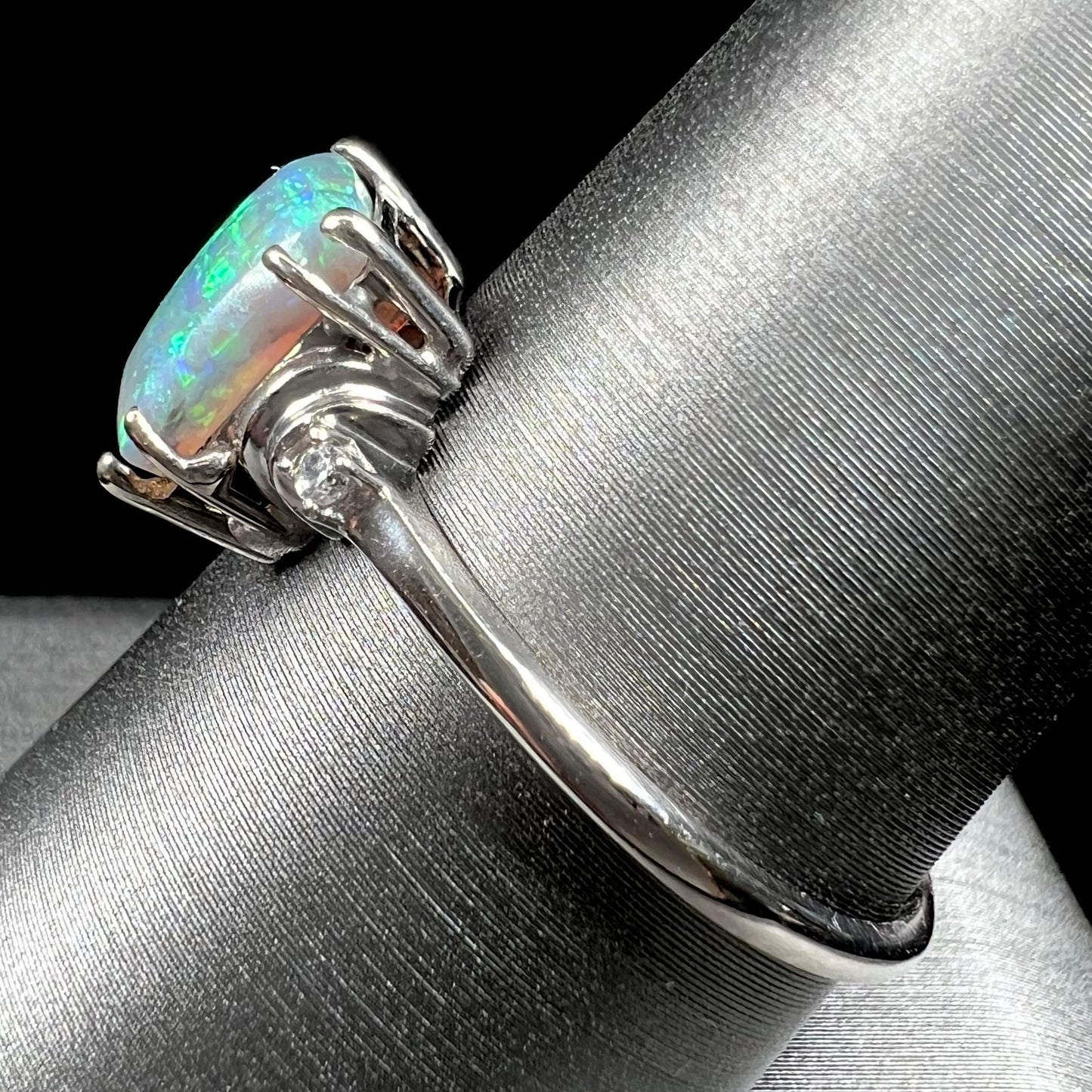 A ladies' white gold ring set with a rectangle cut black opal stone with round white sapphire accent stones.