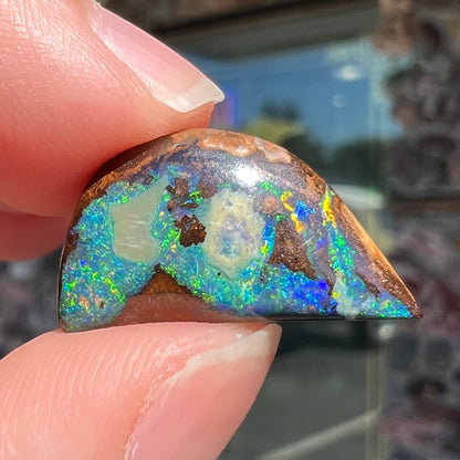 A loose, freeform shaped boulder opal with green and blue multicolor fire from Australia.