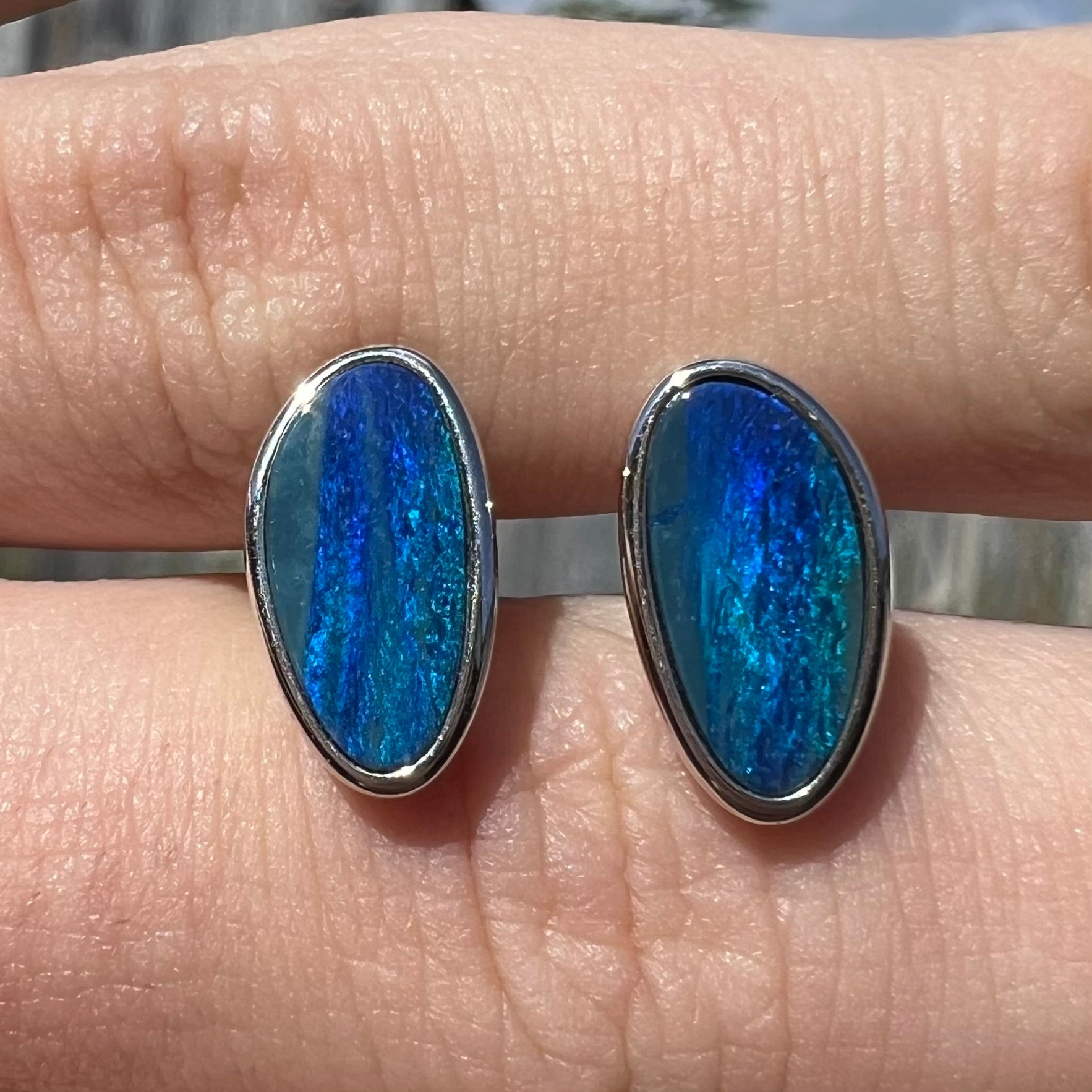 A pair of sterling silver opal doublet stud earrings.  The opals have a vivid blue color.