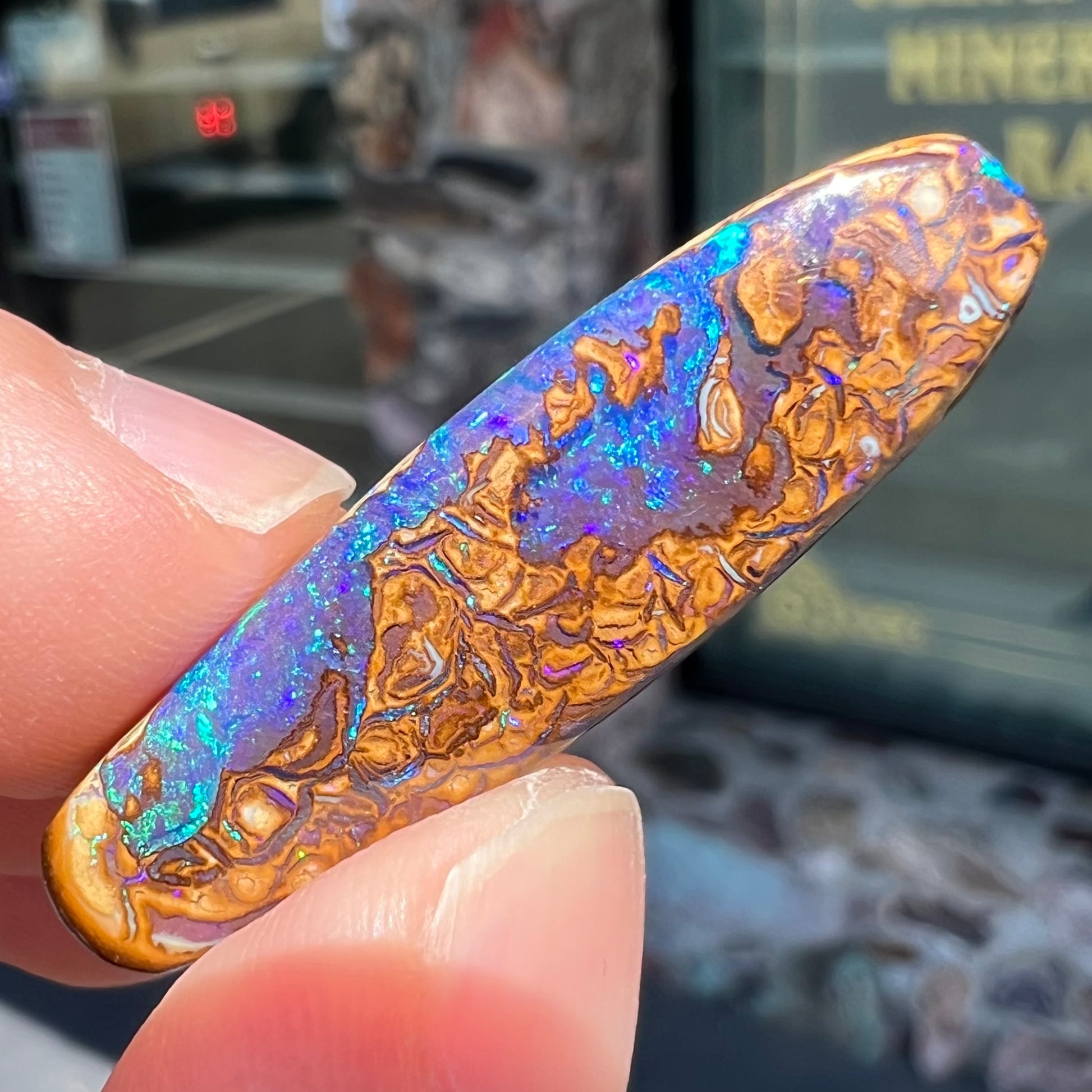 A polished boulder opal stone from Koroit, Australia.  The stone has blue and purple veins.