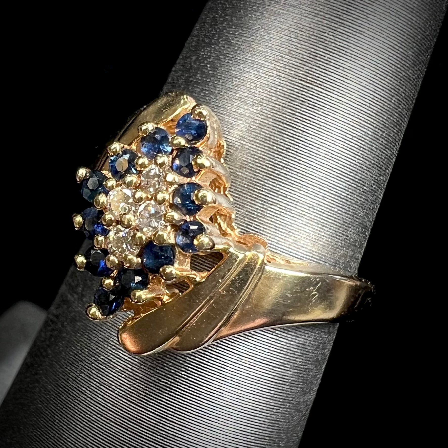 An estate, yellow gold ladies' cluster ring mounted with four round diamonds and twelve round blue sapphires.