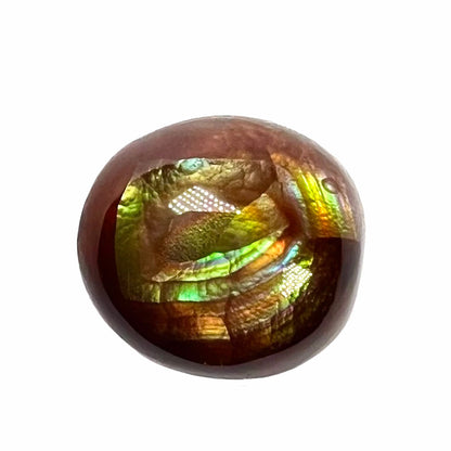 A loose, green, blue, and orange banded fire agate cabochon.