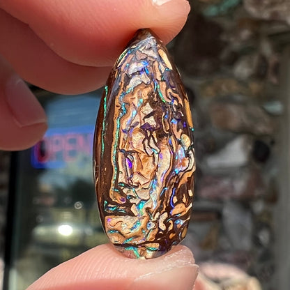 A pear shaped Koroit boulder matrix opal with blue and purple colors in veins.