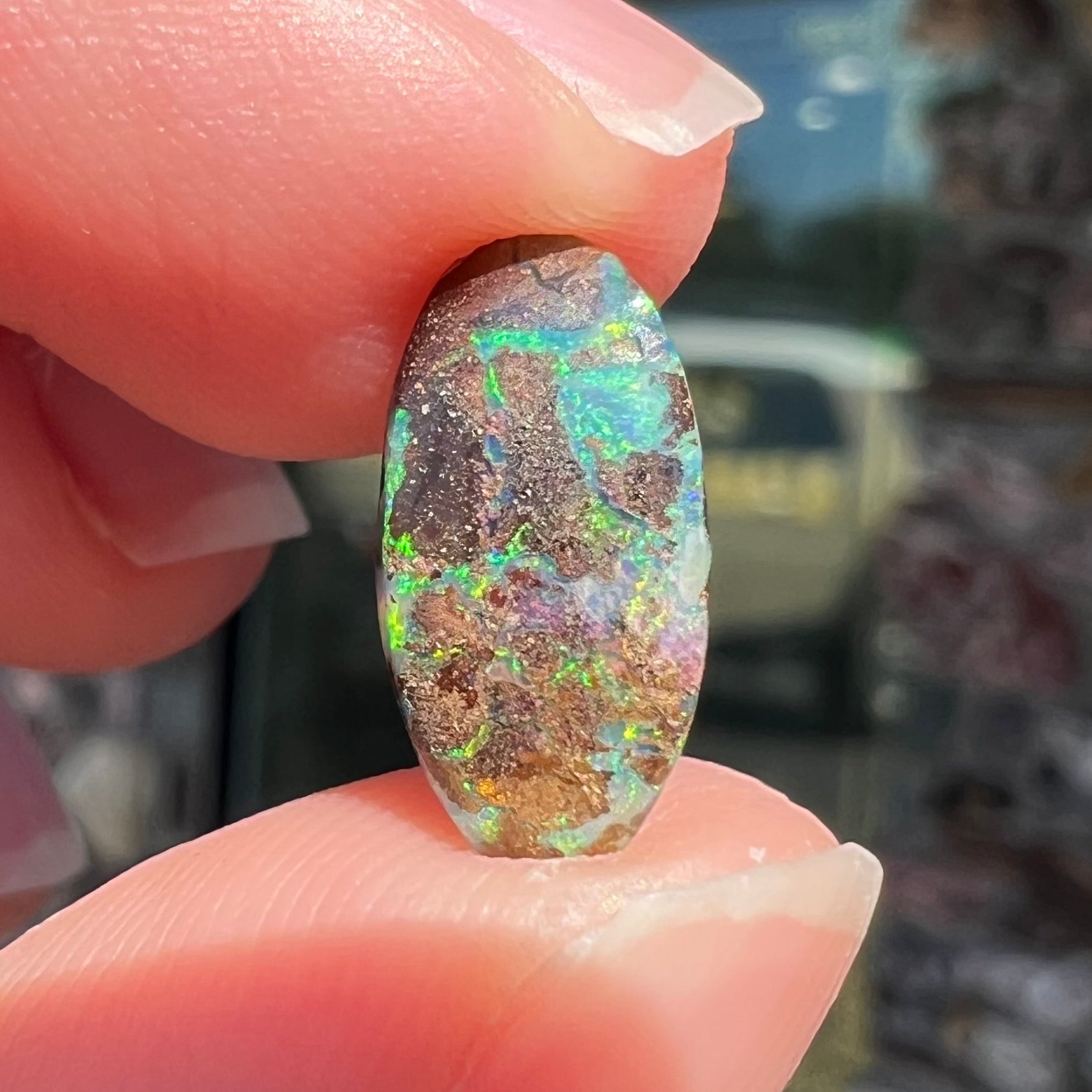 A loose, oval cabochon cut Koroit boulder opal stone.  The opal has a bright green color.