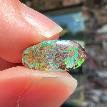 A loose, oval cabochon cut Koroit boulder opal stone.  The opal has a bright green color.