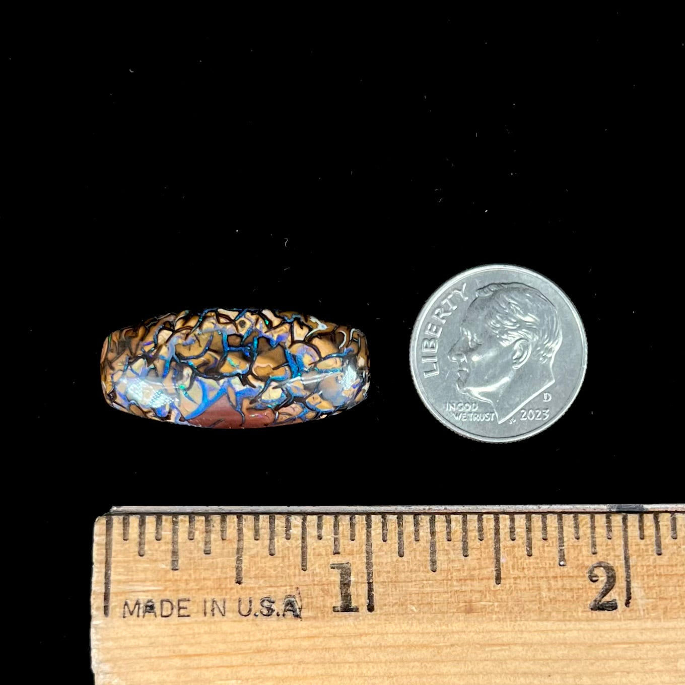 A loose, barrel shaped Koroit boulder opal stone with blue veins.