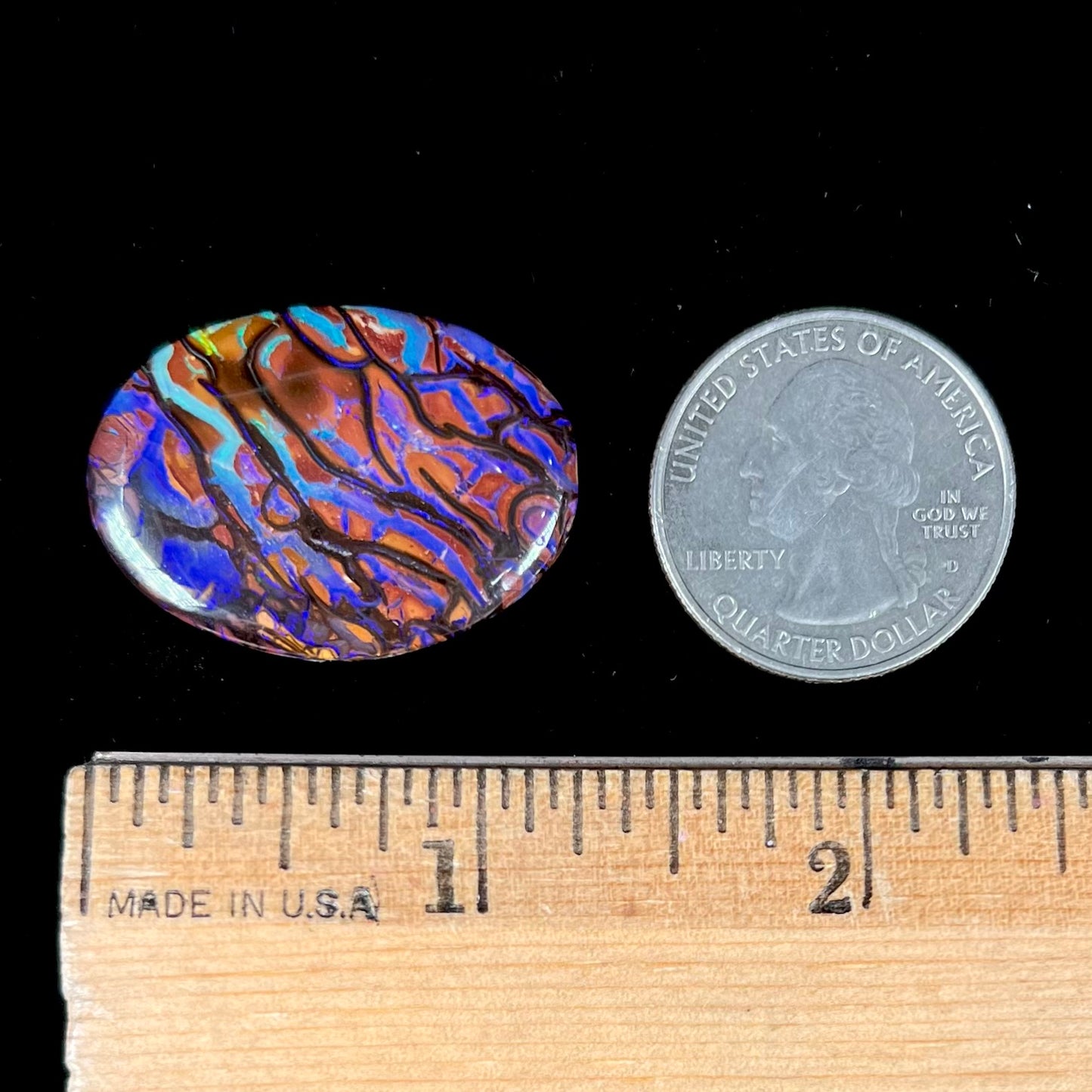 A loose, oval cabochon cut boulder opal from Koroit, Australia.  The opal has violet and purple veins.