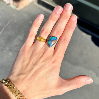 A freeform pear shaped boulder opal stone with blue color.