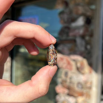 A pear shaped Koroit boulder matrix opal with blue and purple colors in veins.