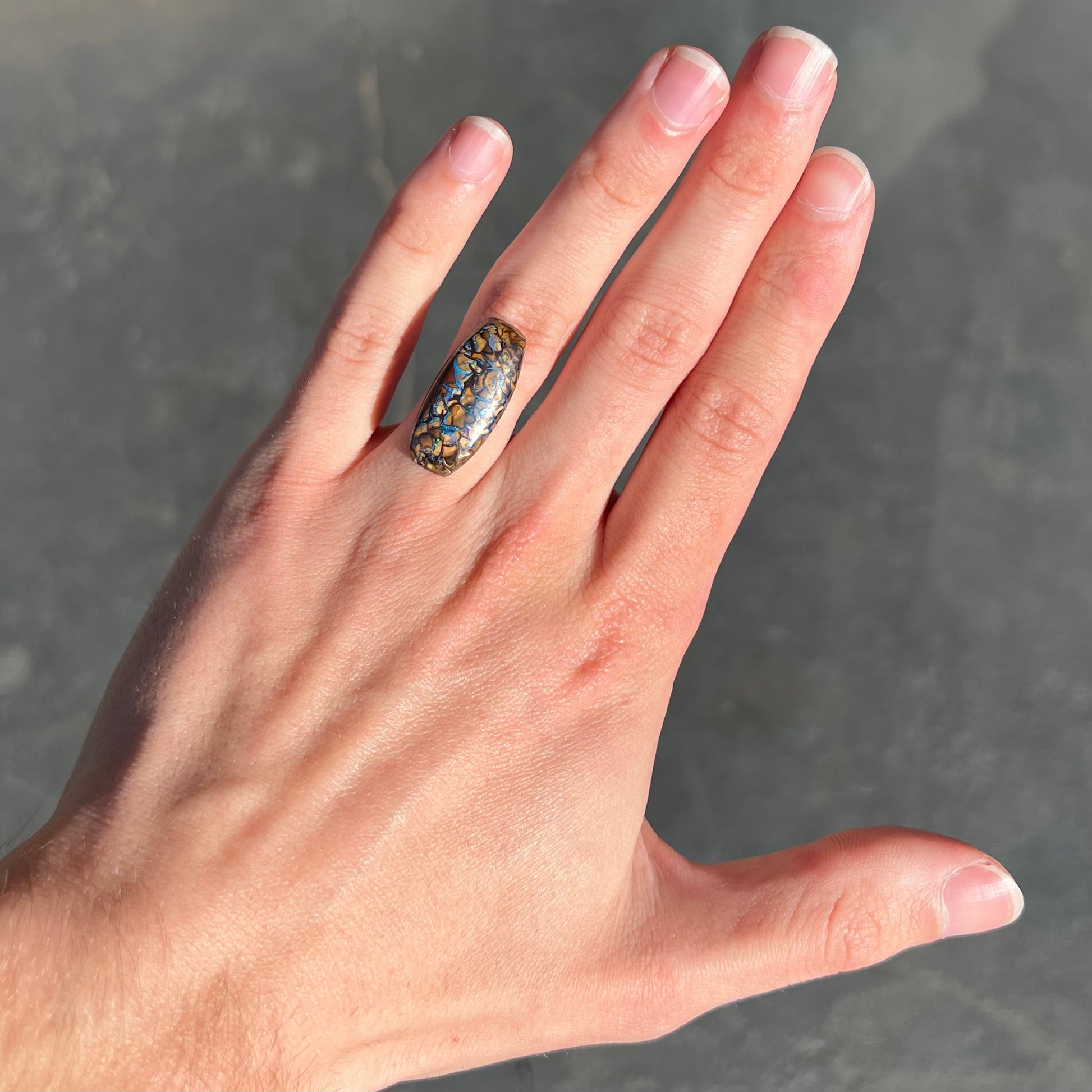 A loose, barrel shaped Koroit boulder opal stone with blue veins.