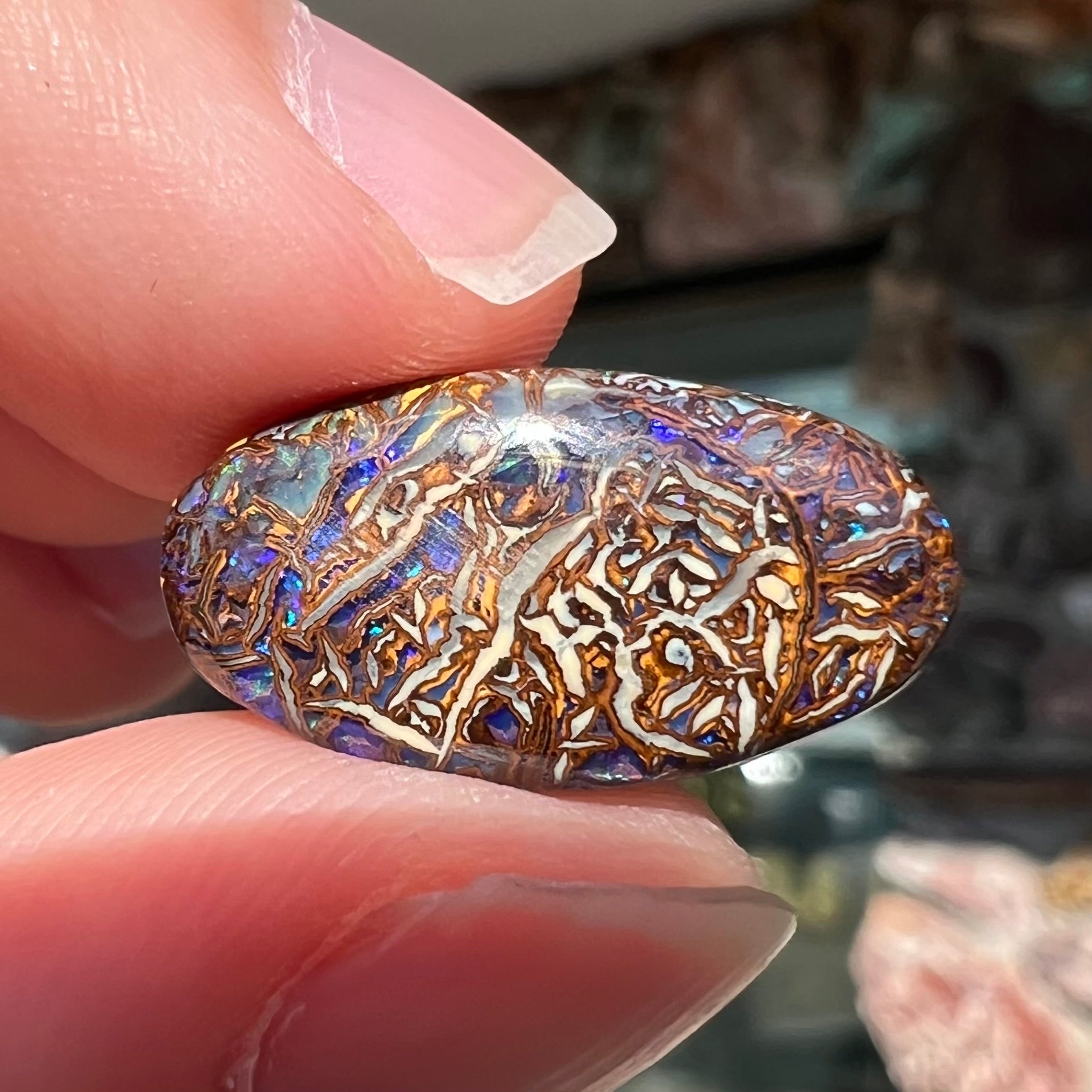 An oval cabochon cut Koroit boulder matrix opal stone.  The opal has blue colors.