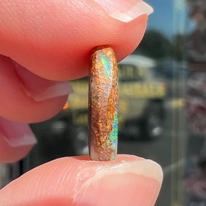 A loose, oval cabochon cut Koroit boulder opal with green fire.