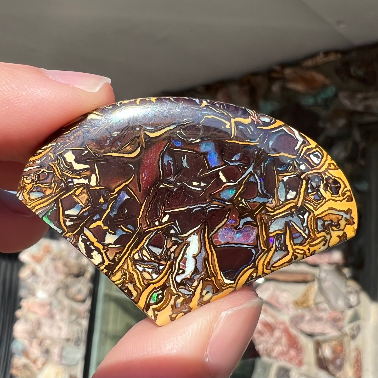 A loose, polished Koroit boulder opal specimen.  The opal has an organic pattern.