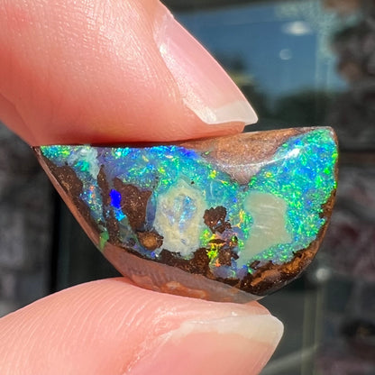 A loose, freeform shaped boulder opal with green and blue multicolor fire from Australia.