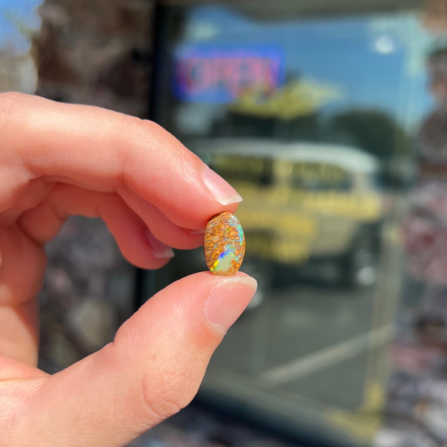 A loose, oval cabochon cut Koroit boulder opal with green fire.