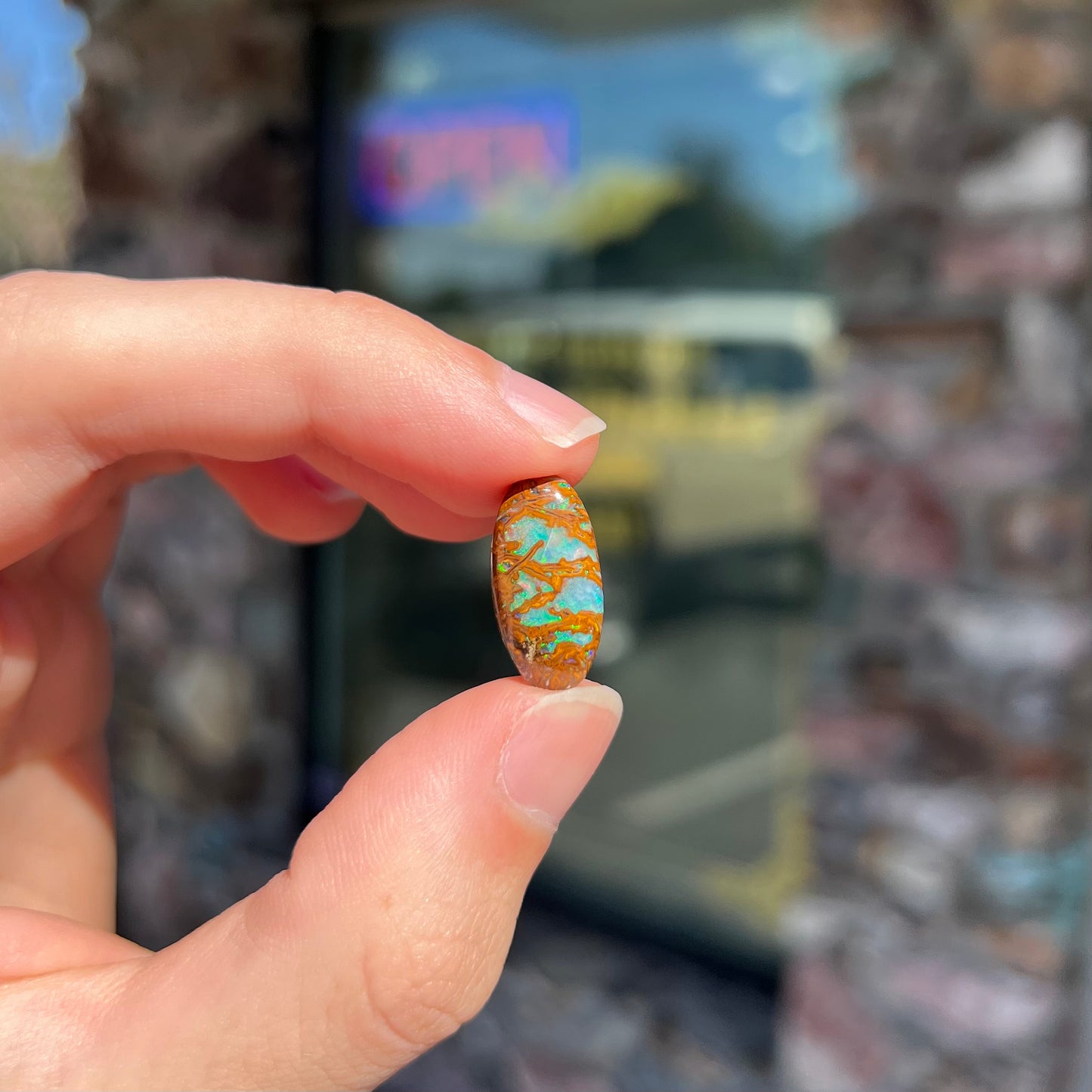 An oval cabochon cut boulder opal stone from Koroit, Australia.  The opal has a blue color.