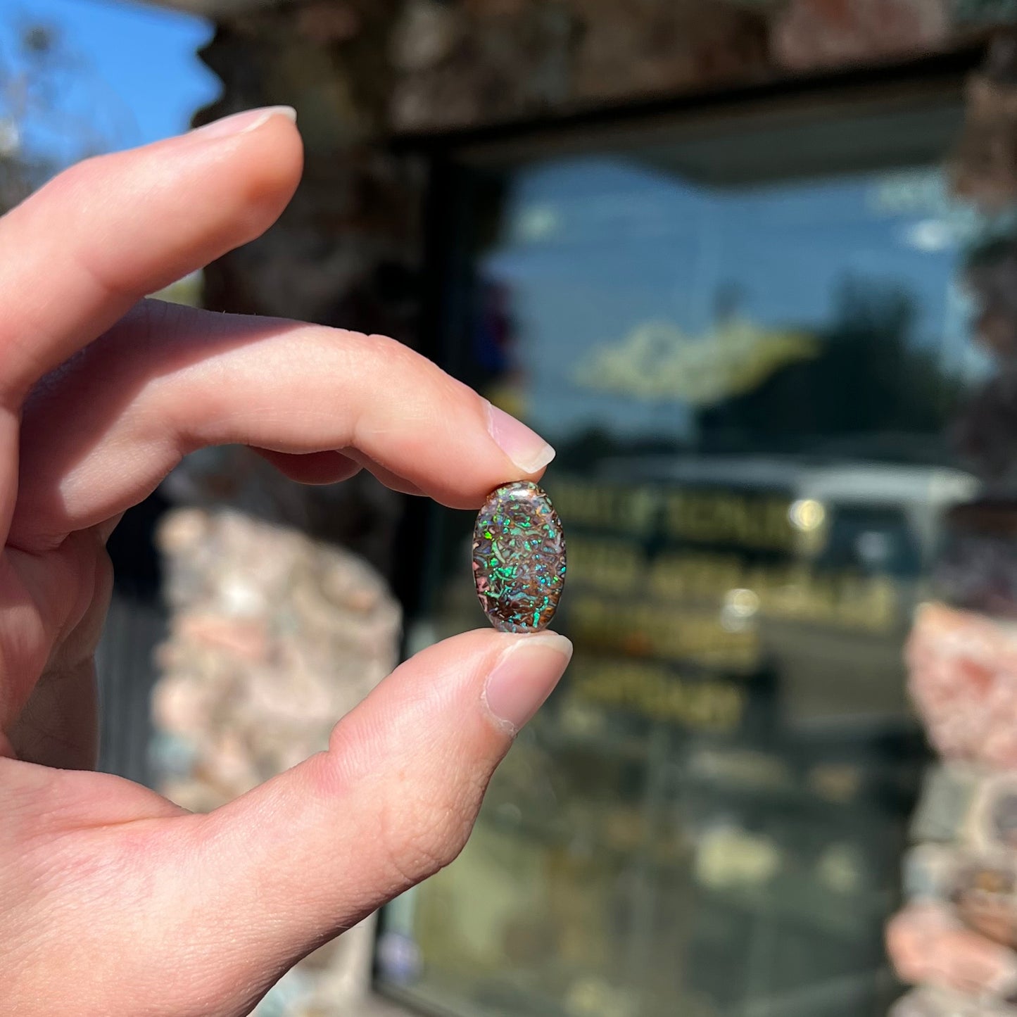 A loose, oval cabochon cut Koroit boulder opal stone.  The opal has green and blue veins.