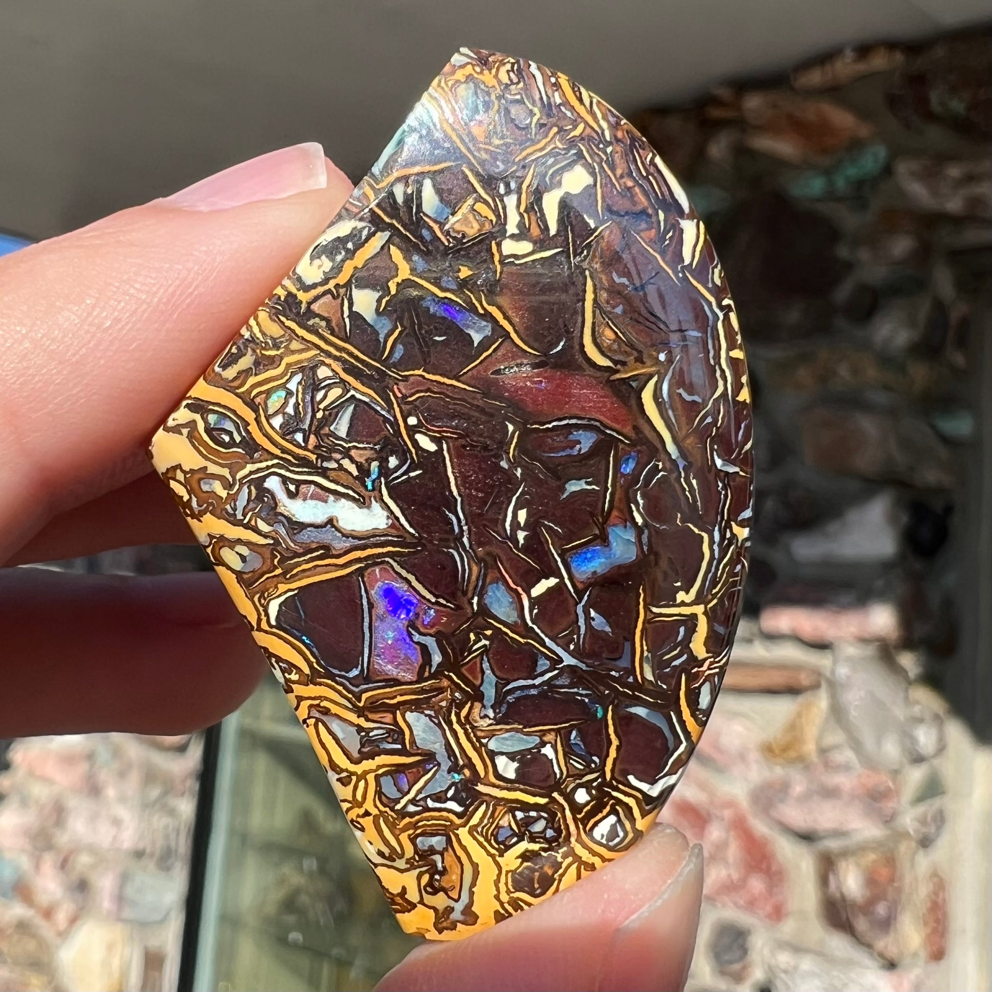 A loose, polished Koroit boulder opal specimen.  The opal has an organic pattern.