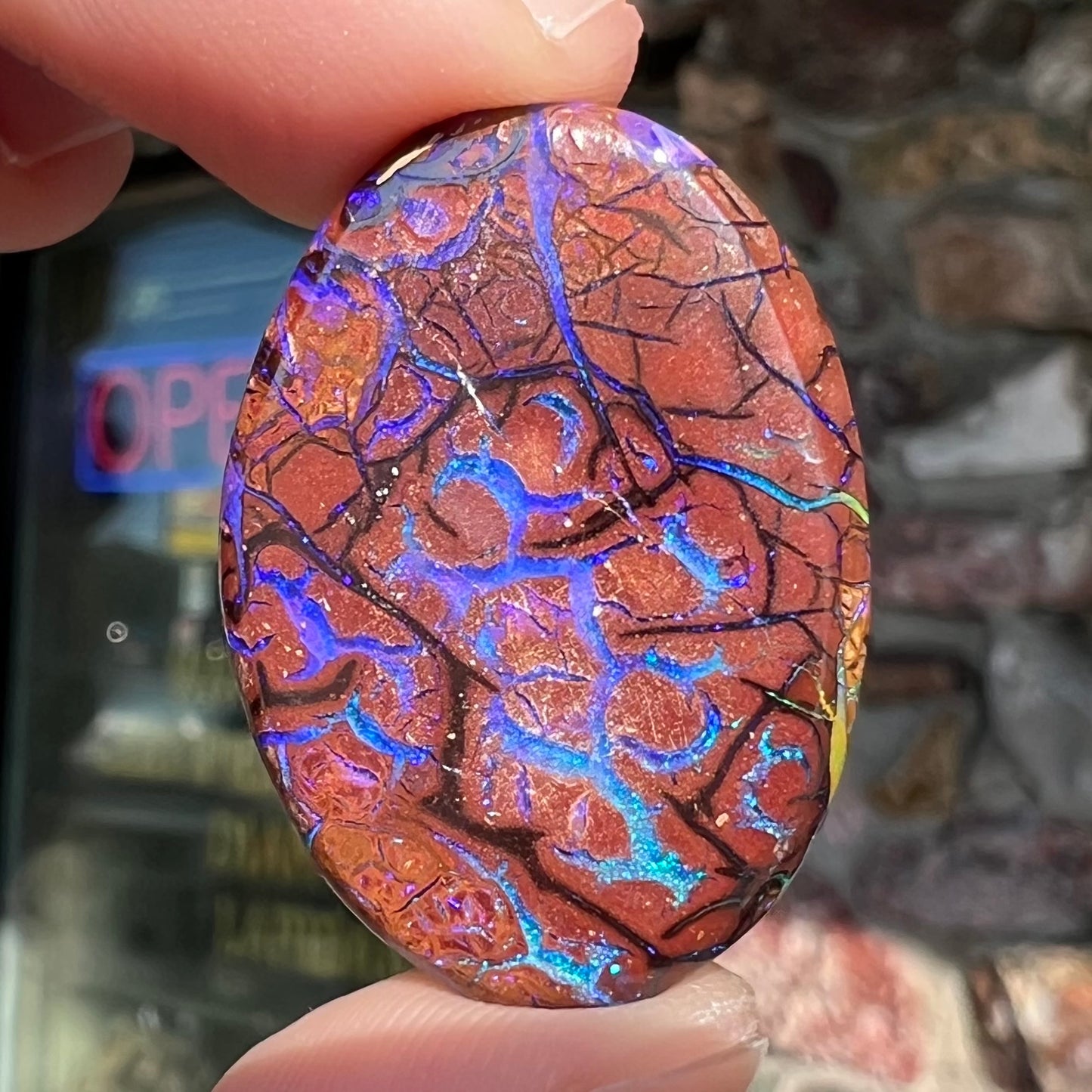 A loose, oval cabochon cut boulder opal from Koroit, Australia.  The opal has violet and purple veins.