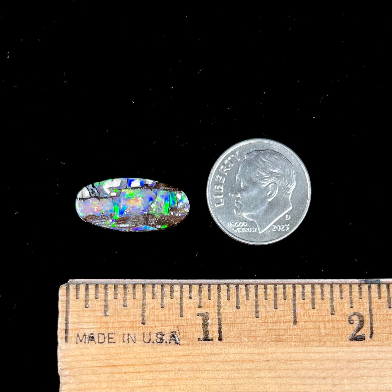 A loose, oval cut boulder opal stone from Koroit, Australia.  The opal shines green and blue colors.