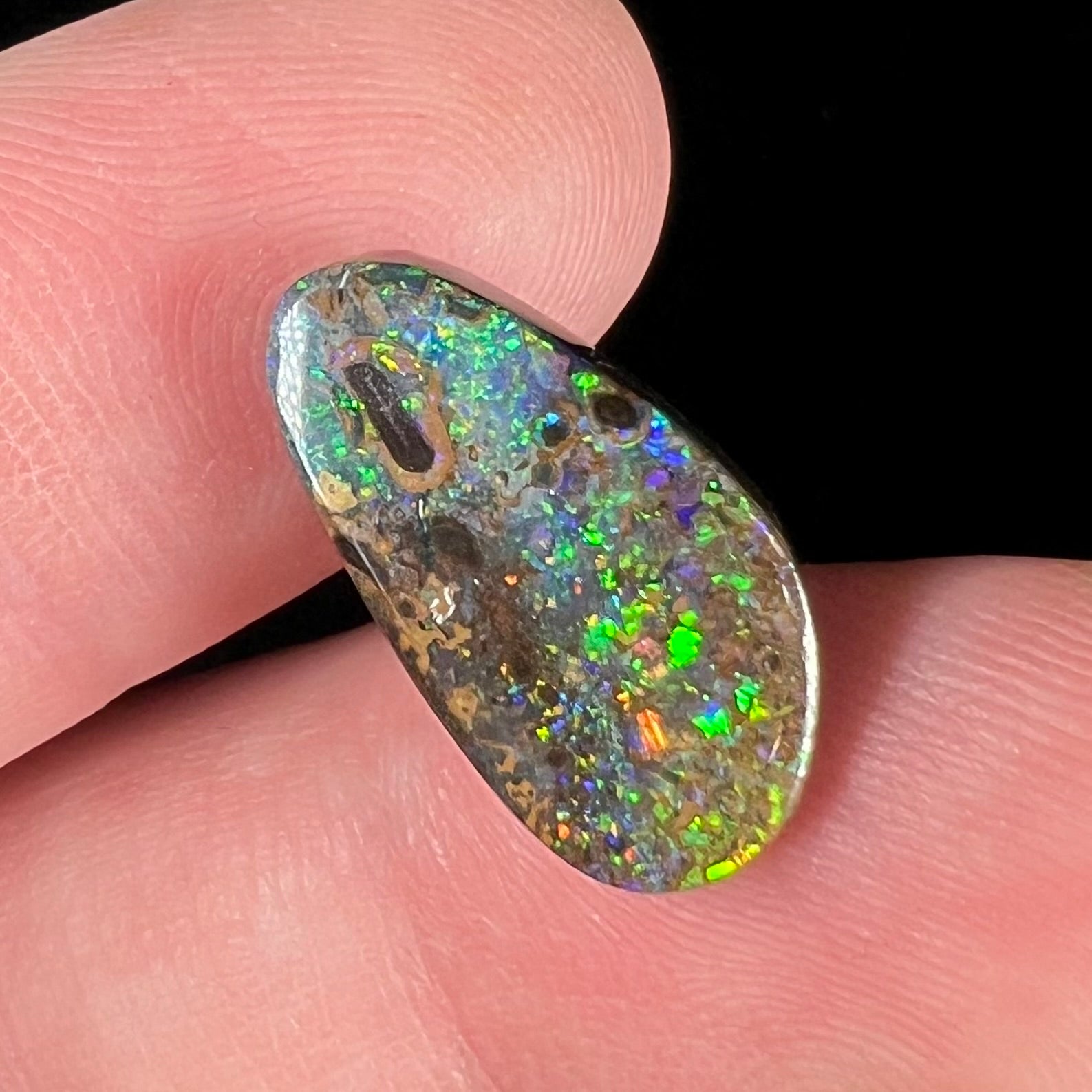 A loose boulder opal stone from Quilpie, Australia.  The opal shines colors of green and orange.