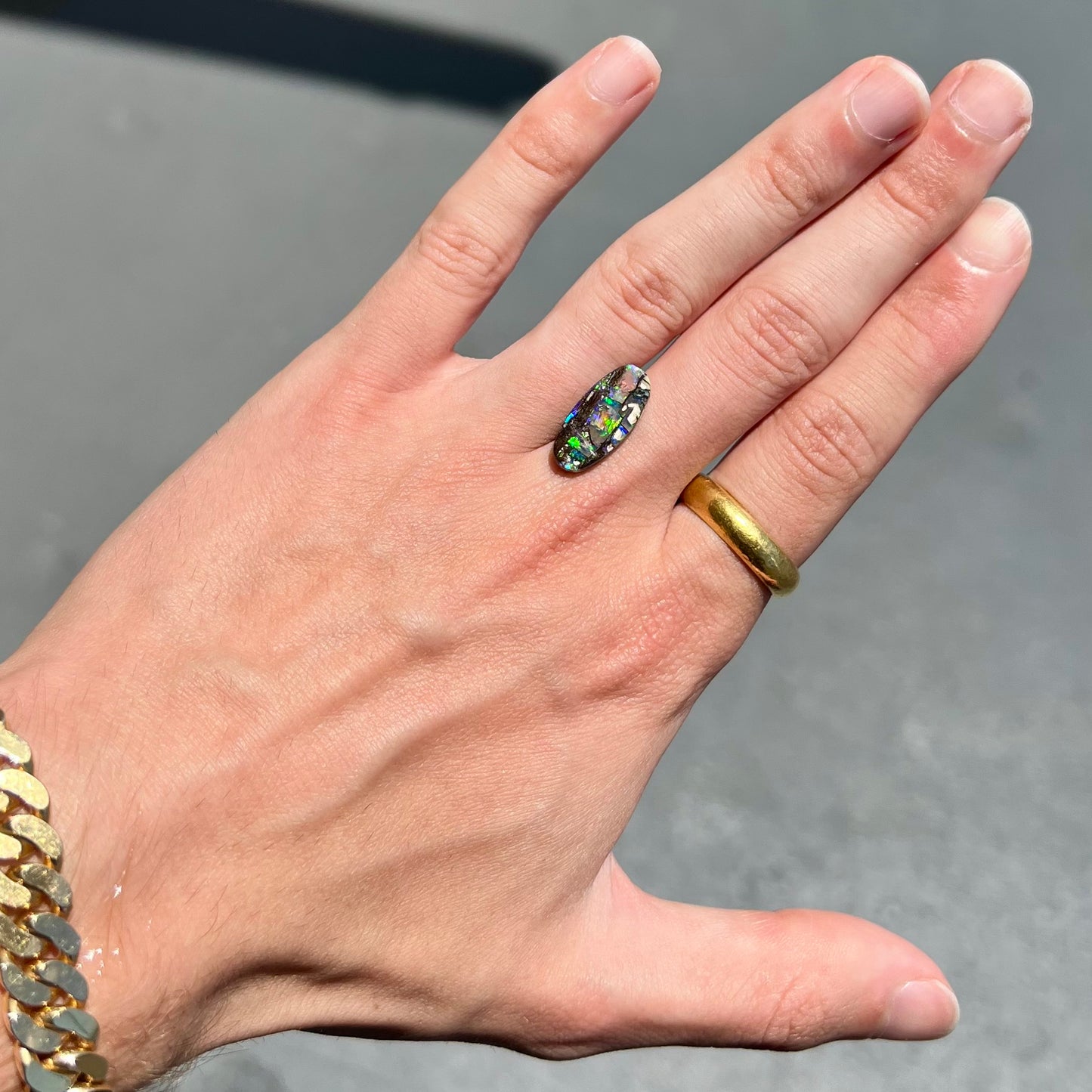 A loose, oval cut boulder opal stone from Koroit, Australia.  The opal shines green and blue colors.