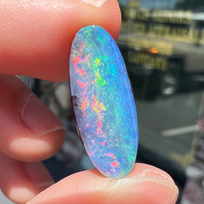 A loose, oval cut rainbow boulder opal gemstone.