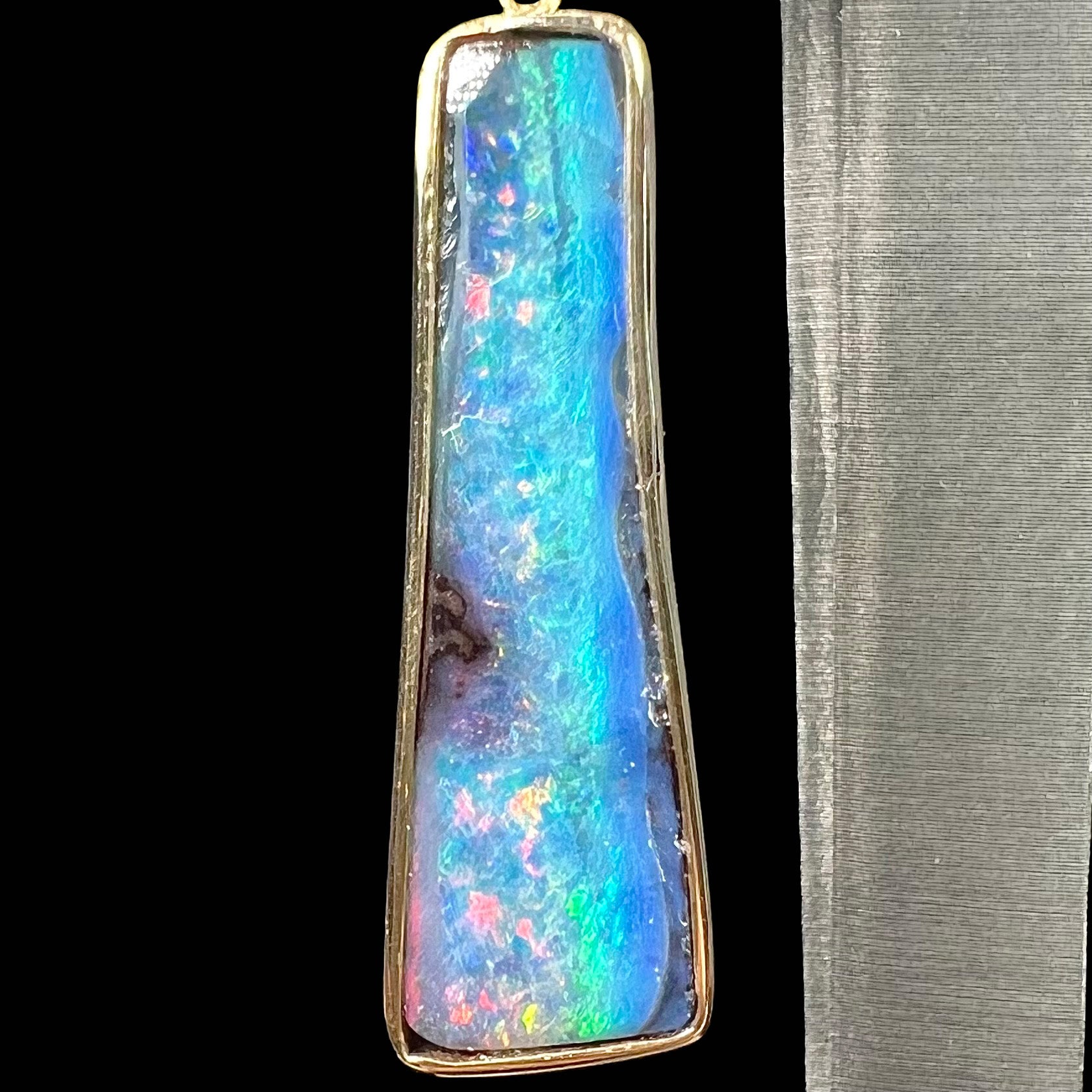 A pair of natural boulder opal dangle earrings set in yellow gold.  The opal displays a rainbow of colors and is from Bull Creek, Australia.