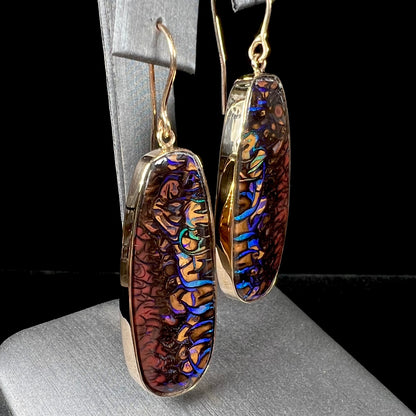 A matched pair of yellow gold patterned boulder opal dangle earrings.  The opals are from Koroit, Australia.