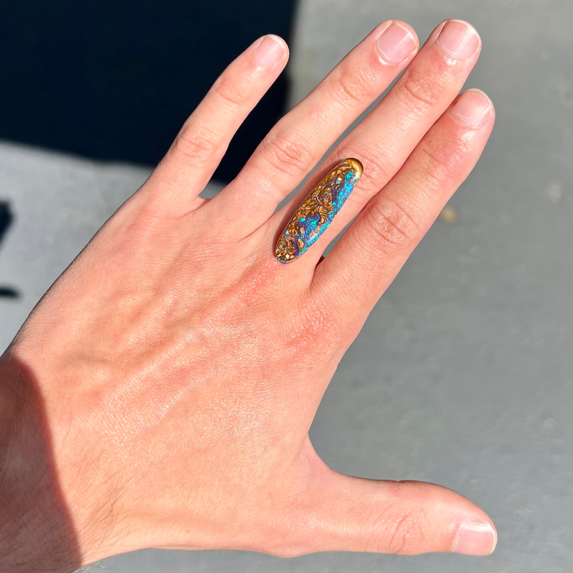 A polished boulder opal stone from Koroit, Australia.  The stone has blue and purple veins.