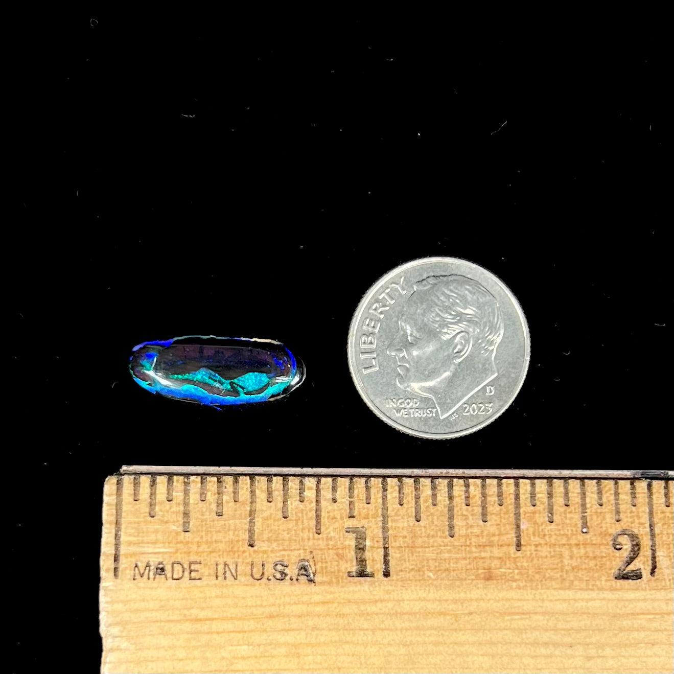 A loose, oval cabochon cut boulder opal stone.  The stone has bright blue and purple veins.