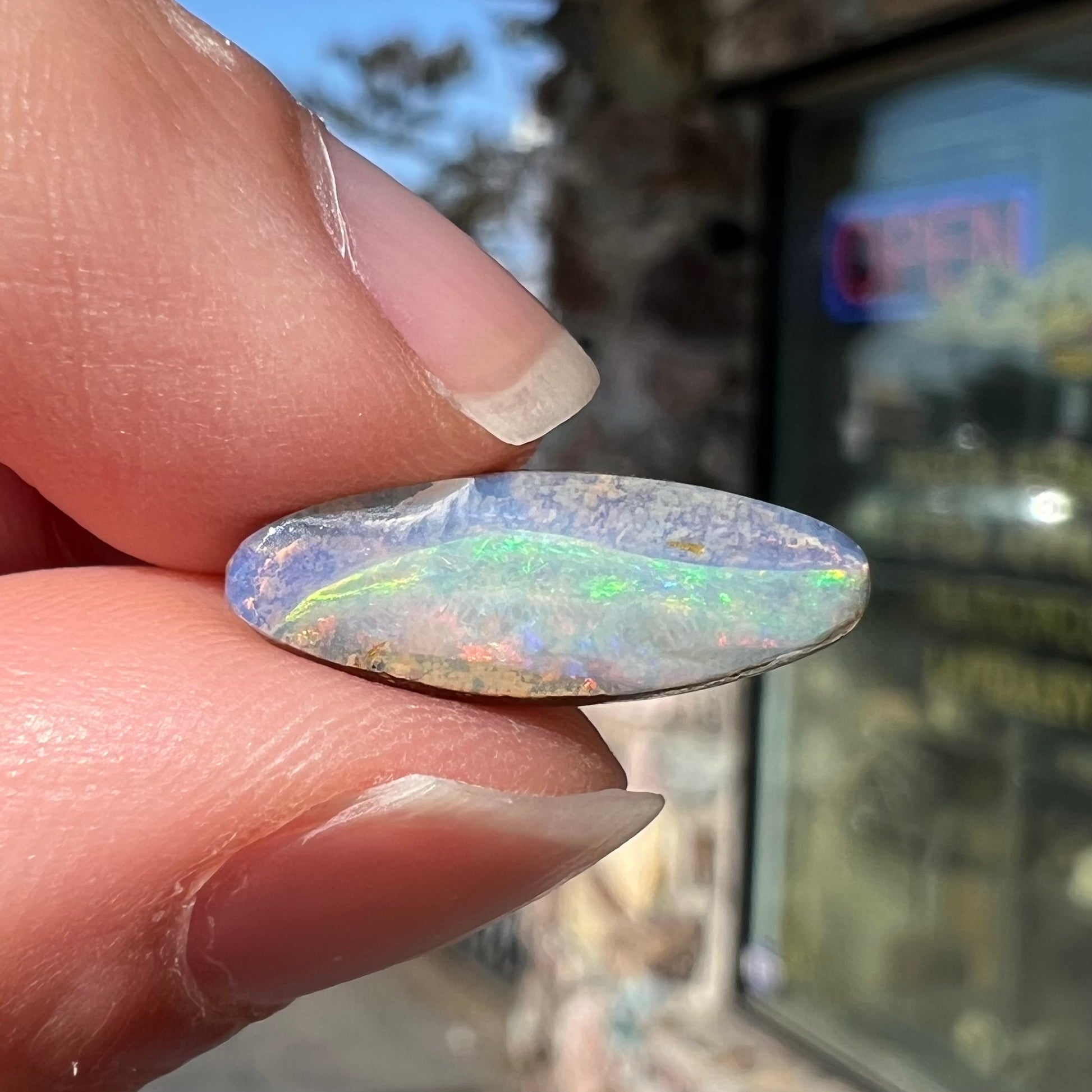 A loose, marquise cut boulder opal from Quilpie, Australia.  The opal has green and red wave patterns.