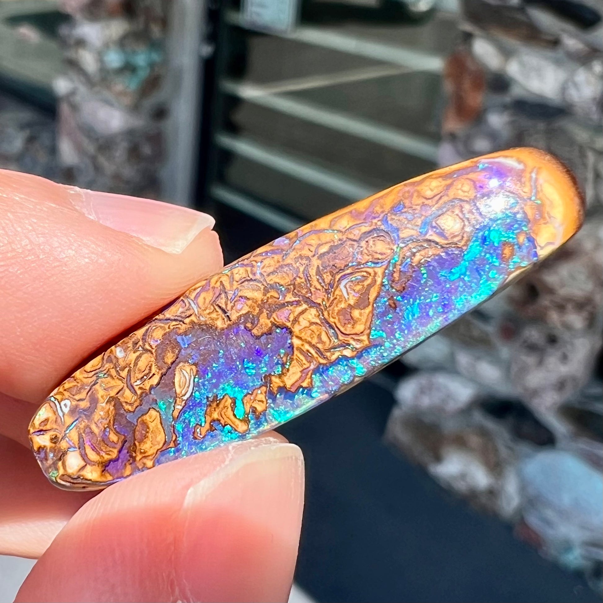 A polished boulder opal stone from Koroit, Australia.  The stone has blue and purple veins.