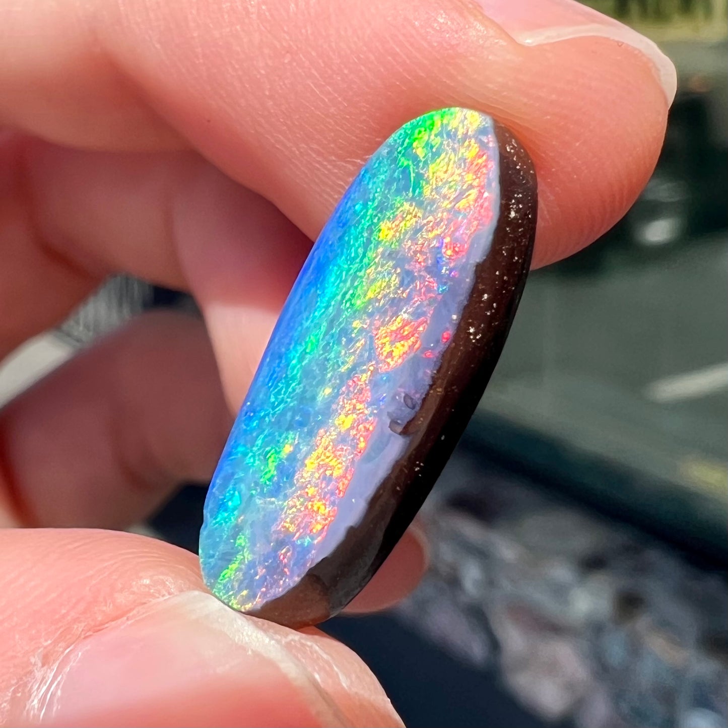 A loose, oval cut rainbow boulder opal gemstone.