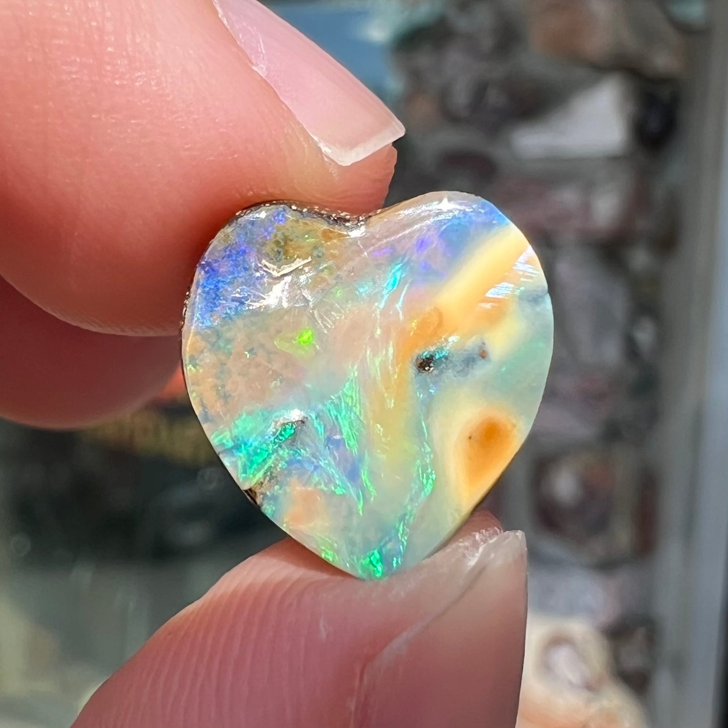 A loose, 5.90 carat heart shaped boulder opal stone from Quilpie, Australia.  The opal has blue flashes.