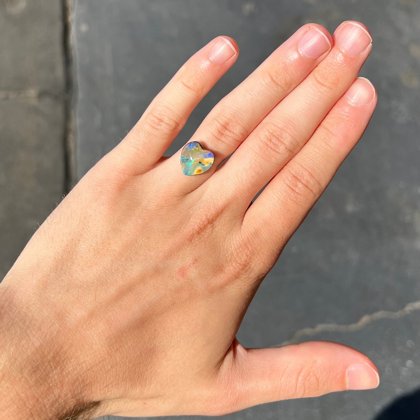 A loose, 5.90 carat heart shaped boulder opal stone from Quilpie, Australia.  The opal has blue flashes.